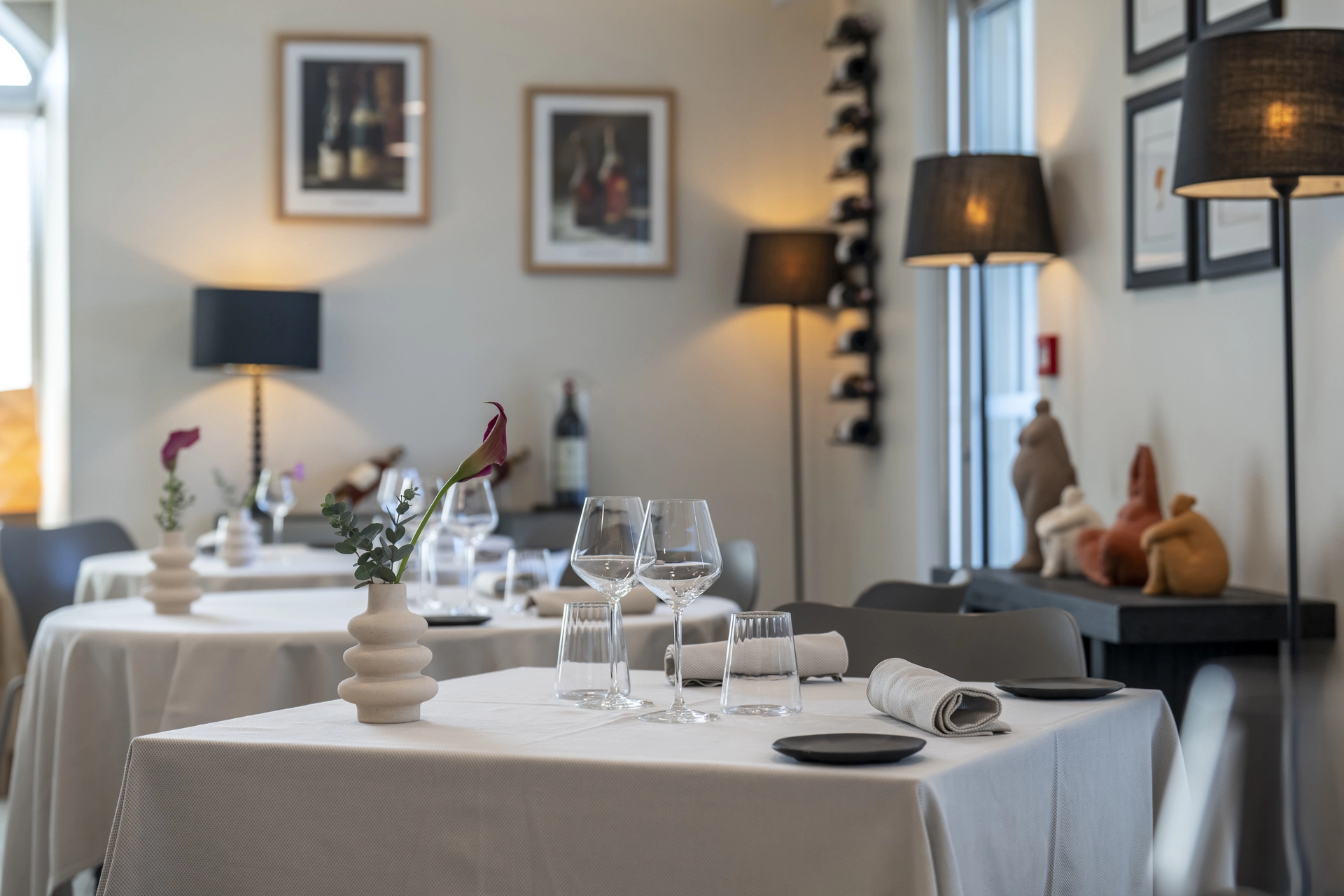 Vue large de la salle principale de l'Auberge d'Arthaz, tables nappes blanches et casier à bouteilles, service du midi