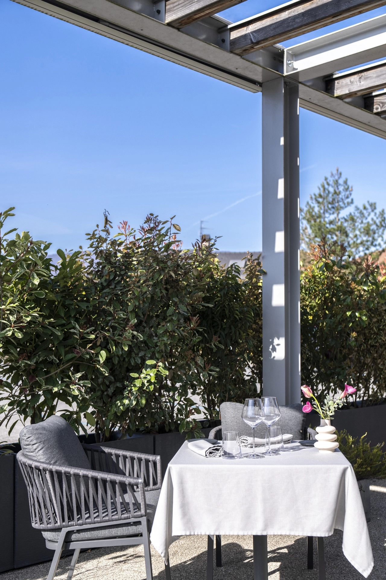 Table ronde sous la pergola ouverte de la terrasse de l'Auberge d'Arthaz, ciel bleu de Haute-Savoie
