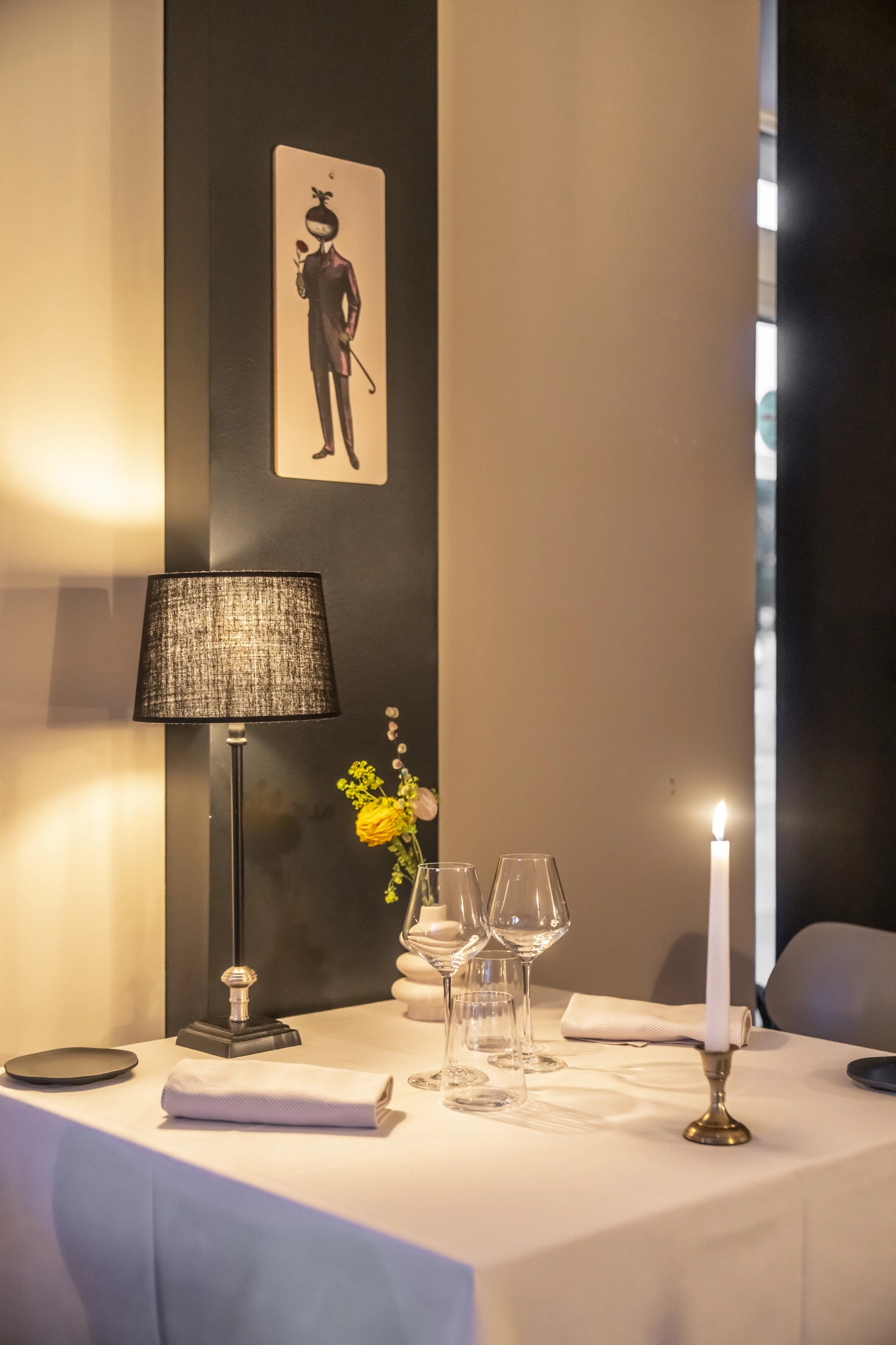 Table pour deux avec bougie haute en laiton et fleurs jaunes, illustration vintage sur cloison noire, Auberge d'Arthaz