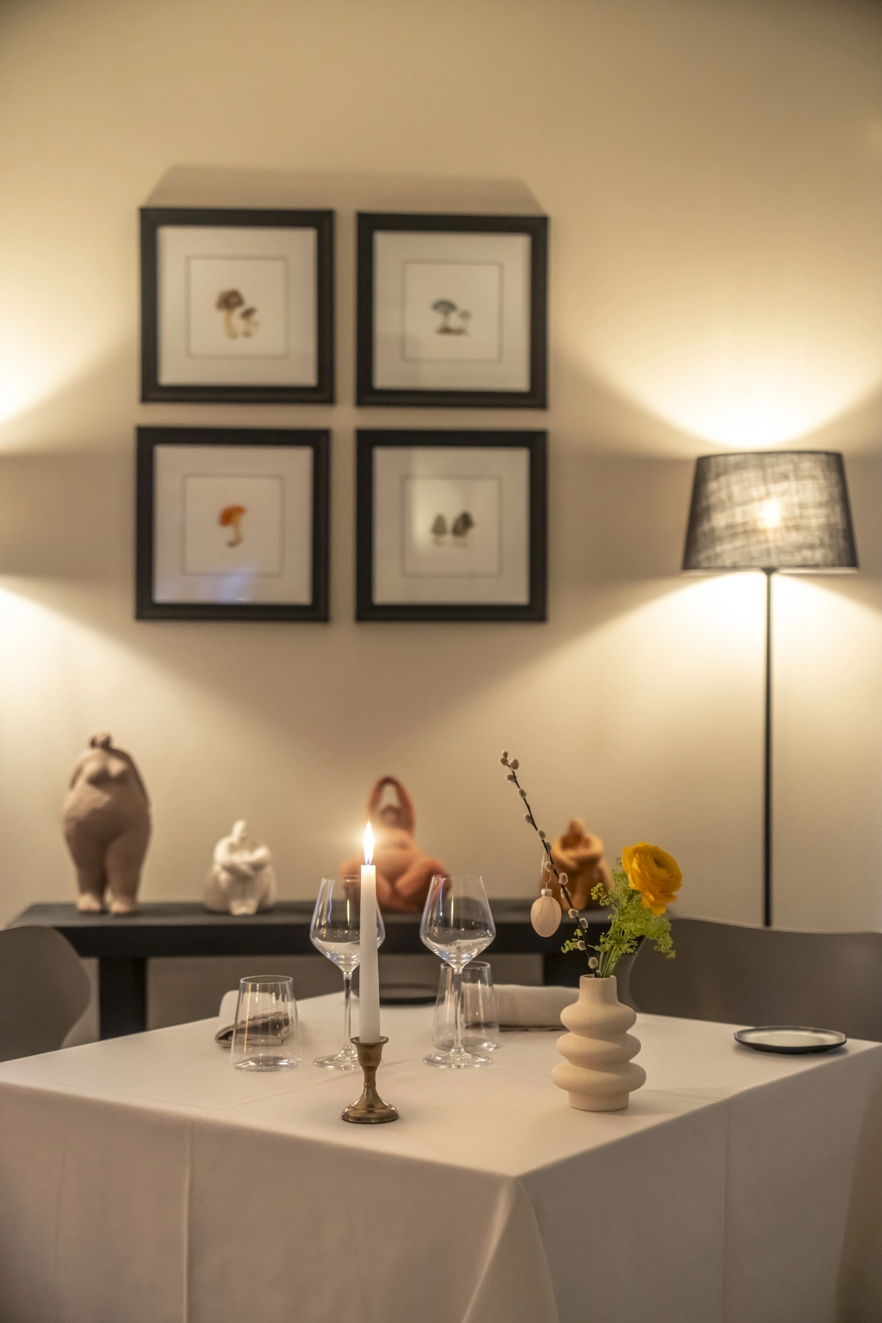 Table pour deux avec bougie et cadres champignons botaniques encadrés, sculptures céramique en fond, Auberge d'Arthaz