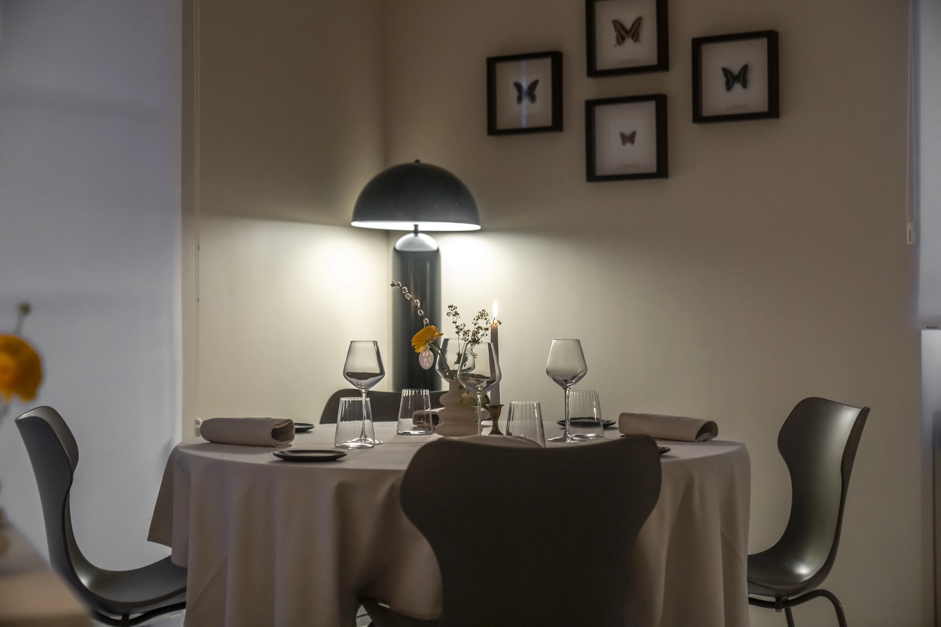 Table dressée pour quatre avec bougie, sous cadres de papillons naturalisés, service du soir à l'Auberge d'Arthaz