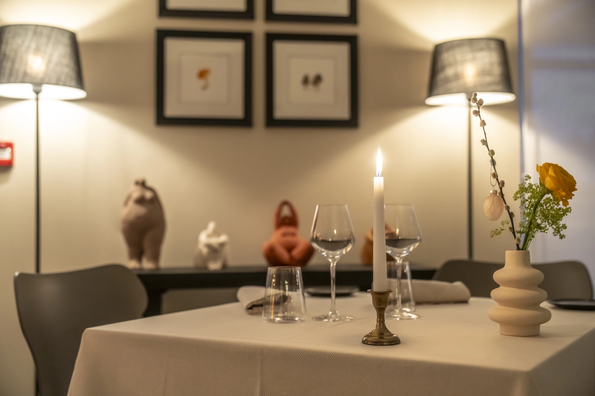 Table dressée avec bougie et fleurs, sculptures céramique en fond et cadres champignons botaniques, Auberge d'Arthaz