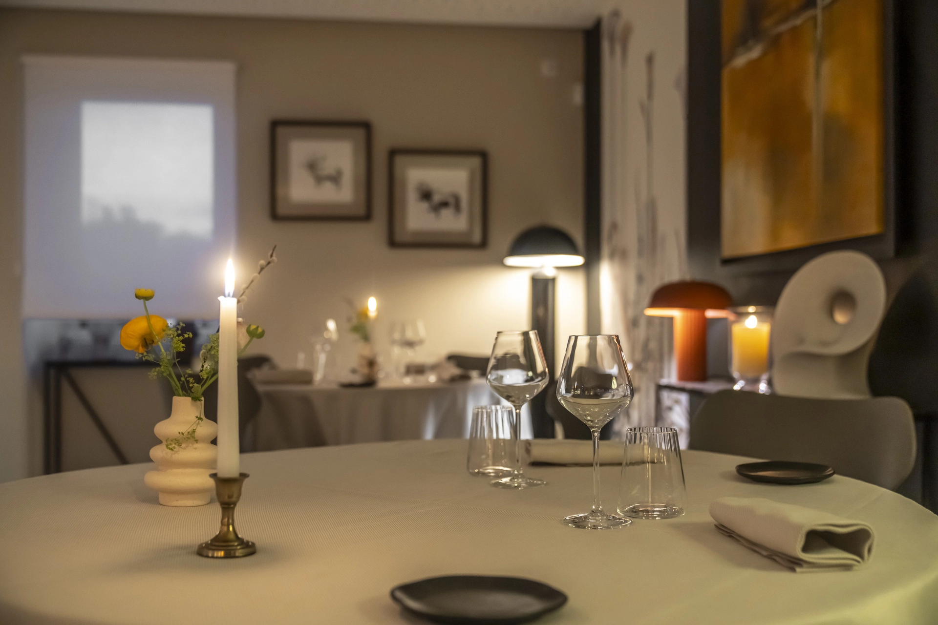 Deux salles communicantes de l'Auberge d'Arthaz vues depuis une table avec bougie, bougies et lumières chaudes