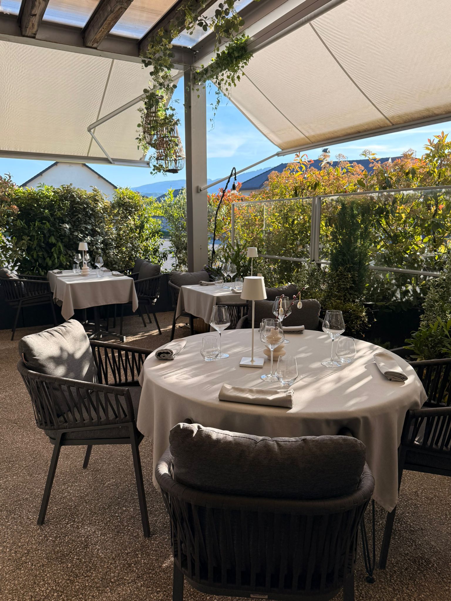 Table ronde dressée sur la terrasse de l'Auberge d'Arthaz avec vue sur les montagnes de Haute-Savoie, ciel bleu dégagé